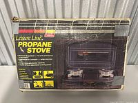 Photo of the original box of Coleman Leisure Line Propane Stove showing the product image, branding, and key features