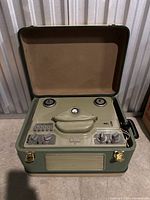 Top-down view of recorder with lid open, showing two tape spindles, central handle and control panel.