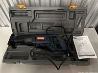 Ryobi reciprocating saw placed inside molded plastic carrying case with instruction manual beside it