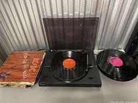 Full view of the Sony record player with a vinyl on the turntable, stack of record sleeves, and another vinyl record beside the player.