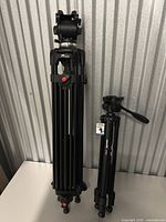 Full view of both tripods standing side by side folded on a white surface.