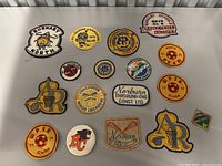 Top down view of 15 mixed vintage patches from various sports teams and clubs mostly related to lacrosse and soccer from the 1970s.