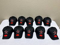 Front view of ten identical black Houston Astros caps