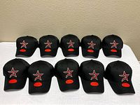 Ten identical black Astros hats displayed front view