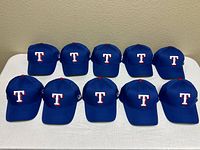 Front view of ten identical Texas Rangers caps lined up on table