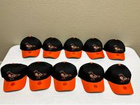 Ten identical Orioles caps arranged on table