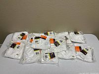 Twelve packaged white Wilson youth baseball pants laid out on table