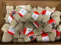 Box containing numerous packaged beige-gold socks