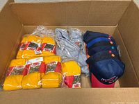 Box contents showing gold socks packages, grey socks bundle and stack of baseball caps