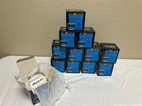 Stack of 12 boxed Dudley softballs with one box open showing wrapped ball