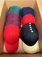 Box containing stacks of assorted-color blank baseball caps