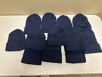 All 12 navy blue beanies laid out on table, showing quantity and uniform style
