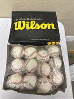 Open Wilson box containing twelve individually wrapped baseballs