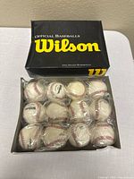 Open box showing twelve individually wrapped Wilson baseballs