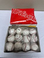 Open Wilson box showing twelve individually wrapped baseballs