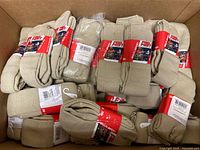 Box containing numerous pairs of tan Pro Feet socks with red bands