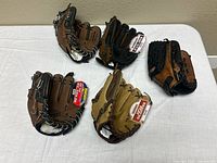 Five baseball gloves displayed on table