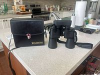 Binoculars standing beside closed Fujinon 2000 case on countertop
