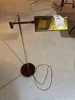 Full view of brass adjustable floor lamp with cord and tag