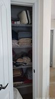 Open closet showing stacked blankets, towels, sheets, pillow