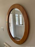 Full view of wood oval wall mirror on wall
