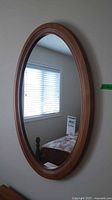 Full view of oval wood framed mirror mounted on wall