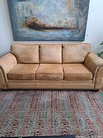 Front view of beige three-seat sofa on rug