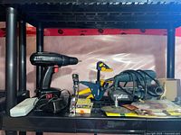 Shelf with drill, staple gun, clamp, sander, sandpaper visible