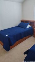 Full view of twin bed with blue cover, headboard shelf visible