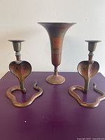Front view of two cobra candlesticks and vase