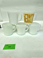 Five milk glass mugs, four plain and one patterned