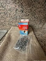 Boxed Rite Aid gel compress and plastic bag containing metal shower hooks on towel