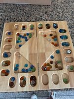 Open folding wooden Mancala board with multicolor glass marbles and die