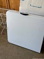 Table folded with handle visible, plastic top, fold line centered