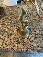 Front view of brass giraffe handle bell on countertop