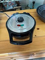 Closed waffle maker showing exterior lid with indicator lights and control knob