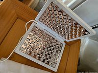 Open light therapy panel showing rose-gold LED arrays and attached power cord