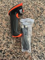 Left side view of barcode scanner beside sealed USB cable