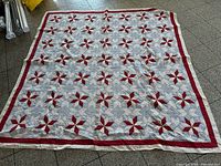 Full view of red grey white patchwork quilt laid flat