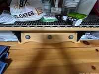 Front view of wood shelf showing three metal pegs and cast-iron brackets