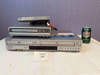 Magnasonic DVD805 on top of Sony SLV-D370P with remotes and cables visible