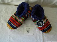 Top view of both slippers showing multicolour pattern and plush lining with tag attached