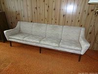 Full front view of four-seat sofa against paneled wall