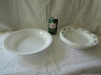Large white bowl, stack of six smaller bowls, soda can for scale