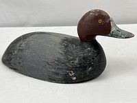Front and side view showing the carved wooden duck decoy with vintage paint and wear.