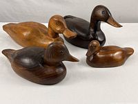 Four carved wood duck decoys arranged together showing size and color differences
