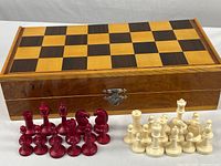 Overall view of the closed wood folding chess set box showing the wood box and checkered playing surface on top.
