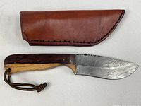 Full hunting knife displayed alongside the brown leather sheath showing overall length and handle detail.