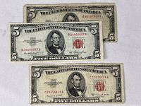 Three Series 1953 and 1953B United States five dollar notes stacked with front designs showing Abraham Lincoln's portrait and red Treasury seals.