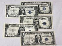 Five 1935 Series U.S. Silver Certificate $1 notes front sides visible showing Series A, B, C, and two E notes with blue treasury seals and George Washington portrait.